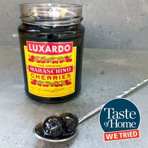 luxardo cherry jar with a spoonful of cherries in the foreground and the taste of home we tried it logo